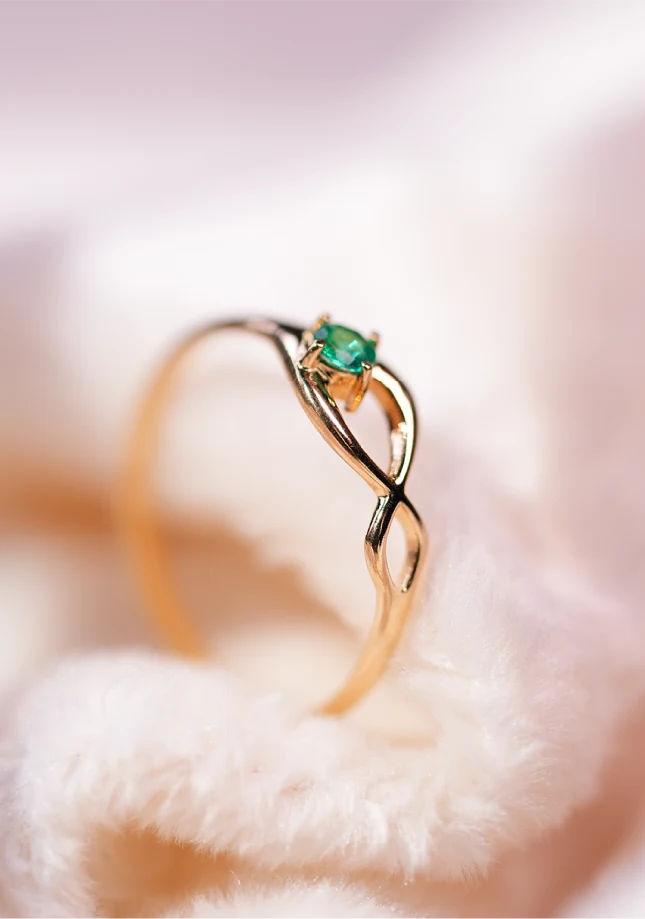 Anillo de oro con esmeralda y banda entrelazada