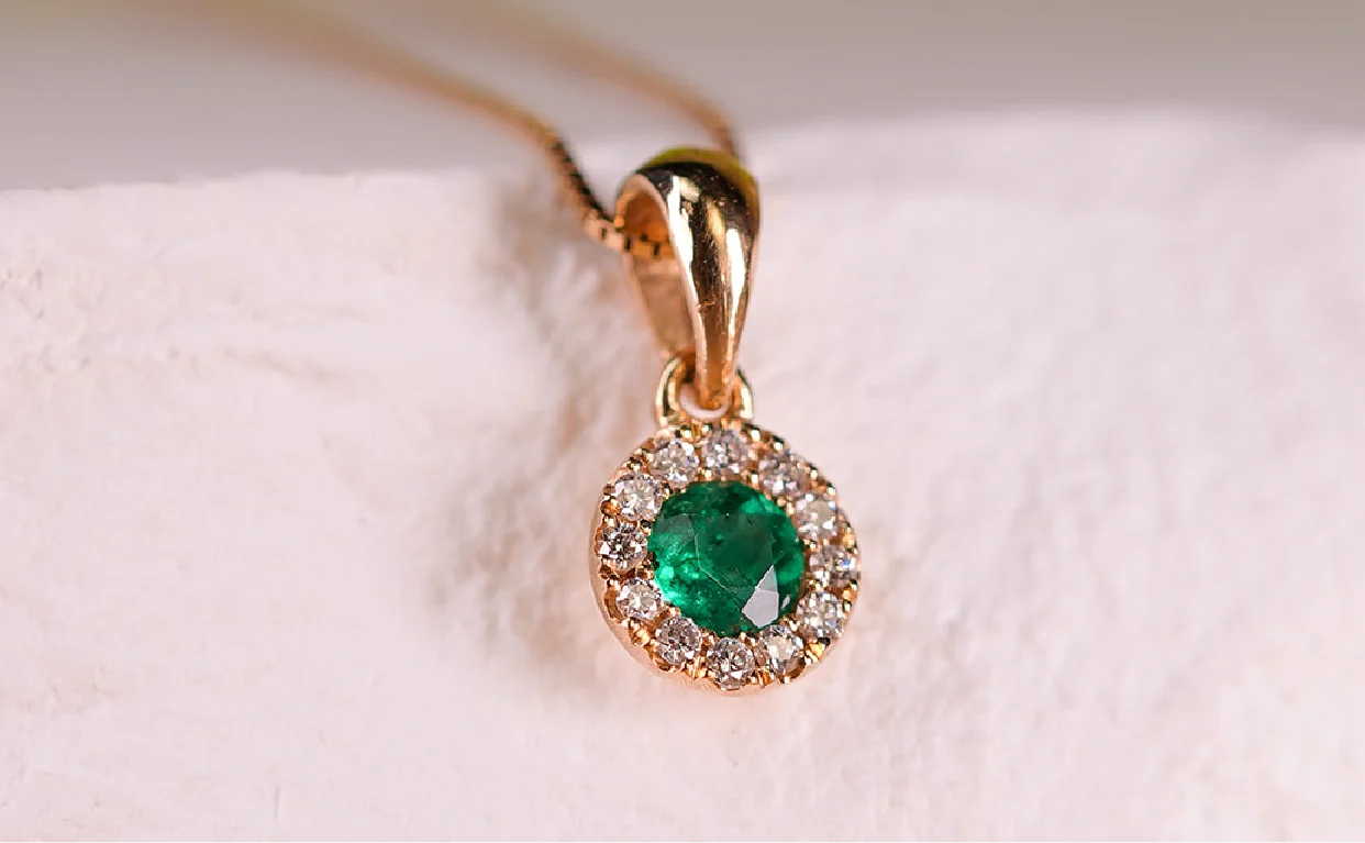 Dije redondo de esmeralda con halo de diamantes en oro