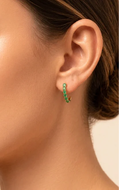 Oreja con arete huggie de esmeraldas